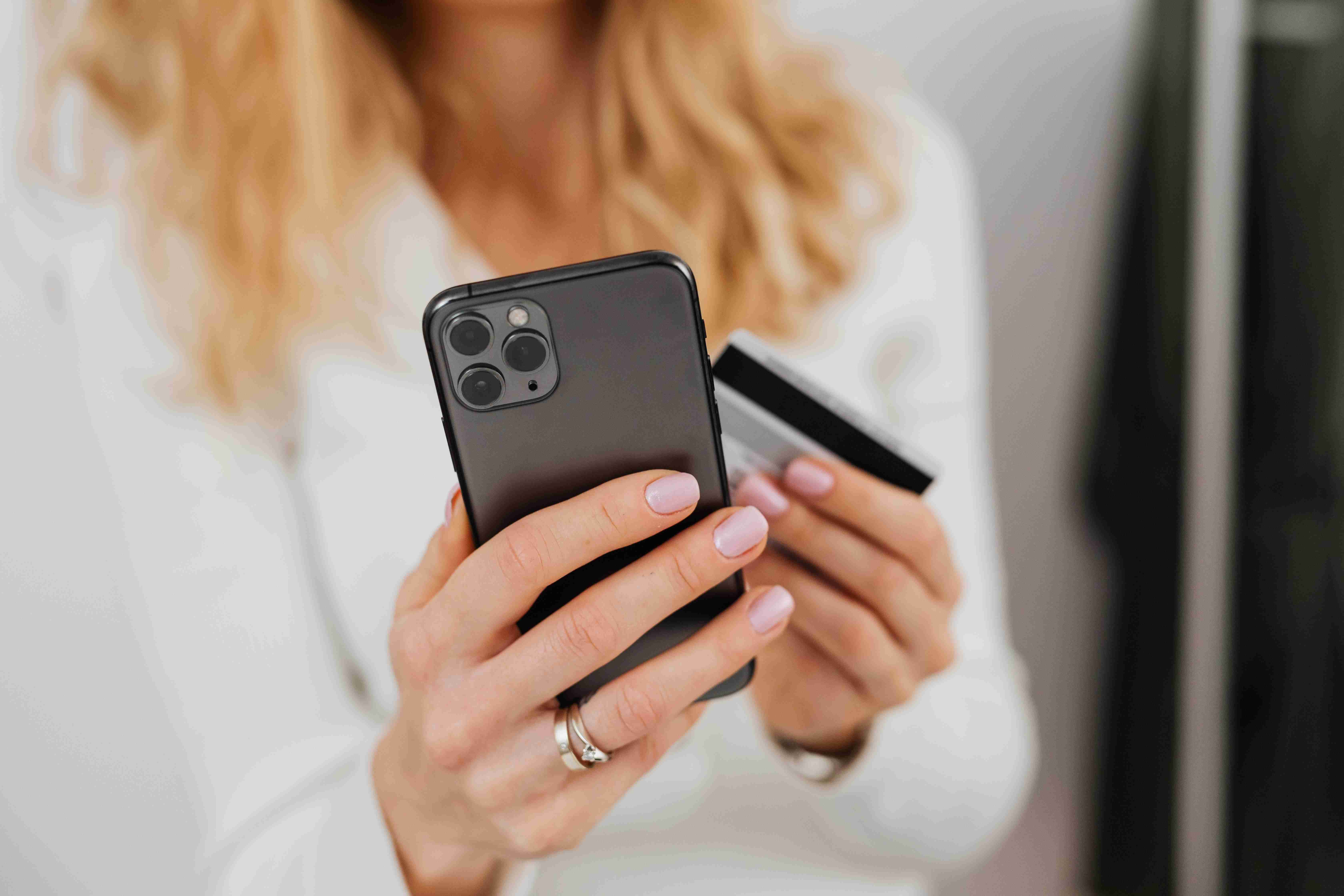 a woman holding a phone with a credit card